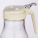 A Tablecraft glass syrup dispenser with a beige plastic top.