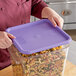 A woman holding a purple Vigor polypropylene food storage container lid with pasta.