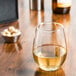 A Libbey stemless white wine glass full of white wine on a table.