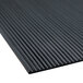 A close-up of the black rubber surface of a Cactus Mat deep groove runner mat with thin stripes.