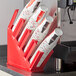 A red Choice countertop cup and lid organizer with white cups in it.