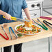 Choice stainless steel tongs with HACCP color coated handles on a table with a plate of food.