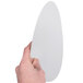 A hand holding a white board lid for a round foil take-out pan.