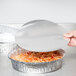 A person using a Durable Packaging foil lid to cover a plate of spaghetti.