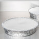 Two Durable Packaging round aluminum board lids on a table.