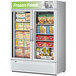 A Turbo Air white swing 2 door freezer with frozen food inside.