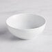 An Acopa Capri coconut white stoneware bowl with a curved edge on a white surface.