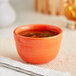 An Acopa Valencia Orange stoneware bouillon cup filled with soup on a table.