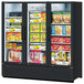 A Turbo Air black swing glass door freezer with different types of food on shelves.