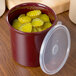 A red Carlisle round plastic crock with a lid and pickles inside.