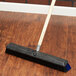 A Carlisle Sparta Spectrum Omni Sweep broom head with black and blue bristles on a wooden floor.