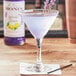 A glass of lavender lemonade with Monin Lavender Lemon Syrup on a table with a napkin.