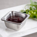 An American Metalcraft stainless steel square sauce cup with barbecue sauce and jalapenos on a white plate.