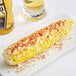 A corn on the cob with Tajin Classic Seasoning on a plate.