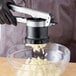 A person using an OXO stainless steel potato ricer to make mashed potatoes.