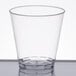 A clear Fineline plastic shot cup on a white surface.
