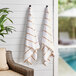 Two Monarch Brands beige striped pool towels hanging on a wall.