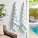 Two Monarch Brands green striped pool towels hanging on a wall.