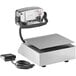 A silver Tor Rey digital portion scale with a cord attached to a white rectangular machine.