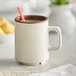 A white GET two-tone melamine mug with brown liquid in it.