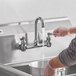 A person wearing gloves and using a Waterloo wall mount faucet.