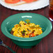 A bowl of food in a GET Diamond Mardi Gras rainforest green melamine bowl on a table.