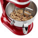 A red KitchenAid stand mixer with a stainless steel bowl full of dough.