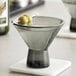 An Acopa gray martini glass filled with olives on a table.