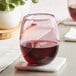 An Acopa mauve stemless wine glass filled with red wine on a coaster.