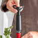 A person using a black and red Vacu Vin wine saver pump on a bottle of wine.