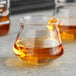 Two Rastal Teku whiskey taster glasses filled with brown liquid on a table.