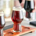 A wooden tray with six Rastal Craft Master One beer tasters filled with beer.