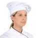 A woman wearing a white Chef Revival chef beret.
