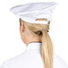 A woman wearing a white Chef Revival chef beret with a ponytail on the back.