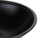 A close up of a black Cambro salad bowl with a white rim.