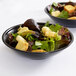 Two black Cambro salad bowls with salad and croutons.