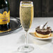 A Libbey Napa Country flute of champagne next to a plate of chocolate cake on a table.