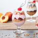 A spoon scooping yogurt into a Libbey Belgian beer/tulip glass filled with granola and fruit.