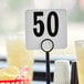 A white American Metalcraft table number 50 sign on a yellow drink counter.