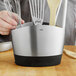 An OXO metal utensil holder on a counter with utensils inside.