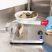 A person in blue gloves using the Vollrath Oyster King to shuck oysters.