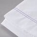 A white Oxford Superblend full size flat sheet with blue stitching.