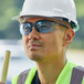 A man wearing a hard hat and light blue Cordova safety glasses.
