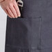 A person wearing an Acopa Kennett blue denim bistro apron with a pocket holding a knife.