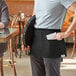 A man holding a black Acopa Kennett denim waist apron with black webbing.
