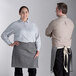 A man and woman wearing gray Acopa Kennett bistro aprons with natural webbing.