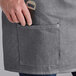 A person holding a knife in the pocket of an Acopa Kennett Gray Denim half bistro apron.