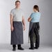A man and woman wearing Acopa blue denim bistro aprons with black webbing.