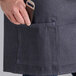 A person holding a knife in the pocket of a blue denim half bistro apron.