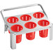 A stainless steel flatware carrier with 6 red plastic perforated cylinders on it.